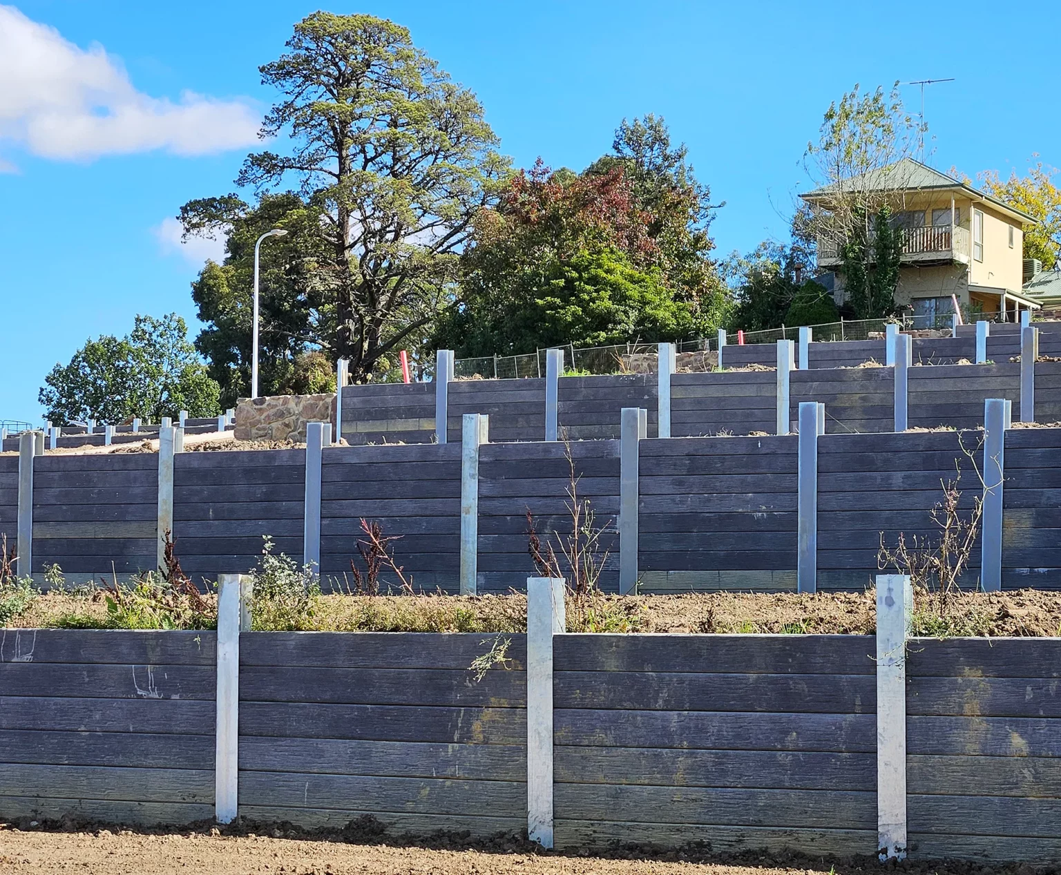 100mm Thick Charcoal Malibu Woodgrain Concrete Sleepers Being Installed on a Large New Estate in Officer and Supplied by Sunset Sleepers