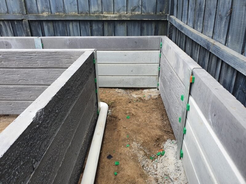 Backyard Garden Bed Retaining Wall Under Construction by Dream View Landscape Using Charcoal Malibu Woodgrain Concrete Sleepers and Supplied by Sunset Sleepers