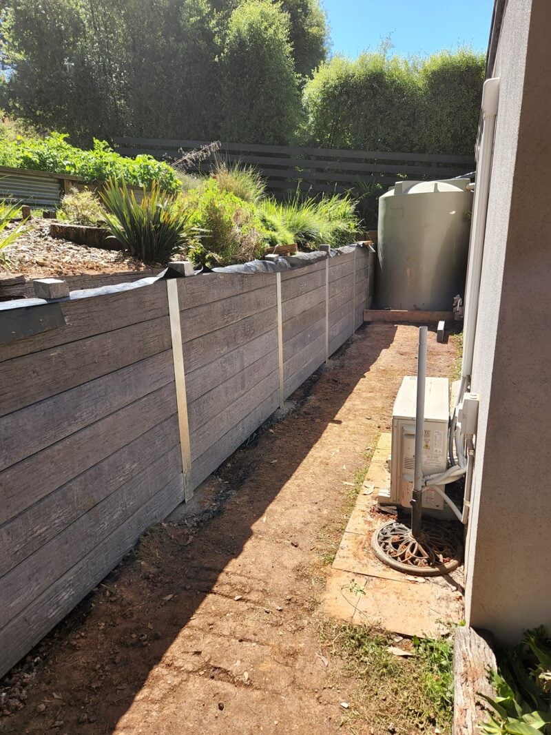 Backyard Retaining Wall Under Construction by Dream View Landscape Using Charcoal Malibu Woodgrain Concrete Sleepers and Supplied by Sunset Sleepers