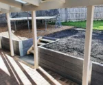 Charcoal Malibu Woodgrain Concrete Sleepers Installed in a Backyard Retaining Wall Along a Stairwell and Supplied by Sunset Sleepers