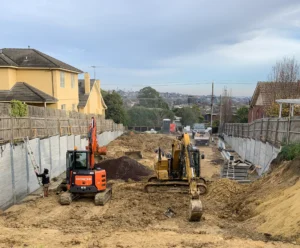 Large Boundry Retaining Wall Being Constructed using The Marina Smooth Concrete Sleepers in Plain Grey - Constructed by the team at JBS Retaining Walls & Excavations and Supplied by Sunset Sleepers