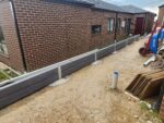 Small Side of House Boundary Retaining Wall Being Constructed by Dream View Landscape Using Charcoal Malibu Woodgrain Concrete Sleepers and Supplied by Sunset Sleepers