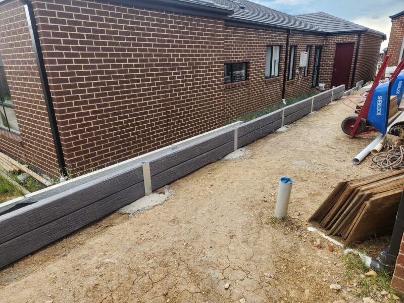 Small Side of House Boundary Retaining Wall Being Constructed by Dream View Landscape Using Charcoal Malibu Woodgrain Concrete Sleepers and Supplied by Sunset Sleepers