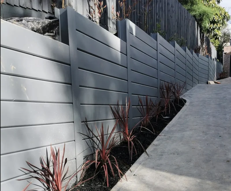 The Marina Smooth Concrete Sleepers 100mm Thick With 150UC23.4 Steel Posts All Painted Grey Along Driveway and Supplied by Sunset Sleepers